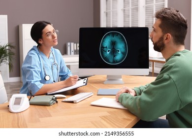 Neurologist Consulting Patient At Table In Clinic