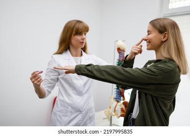 Neurologist performing neurological tests on young female patient. Doctor checks the coordination of the patient's movements and asks to touch the tip of your finger to the nose with your eyes closed - Shutterstock ID 2197995835