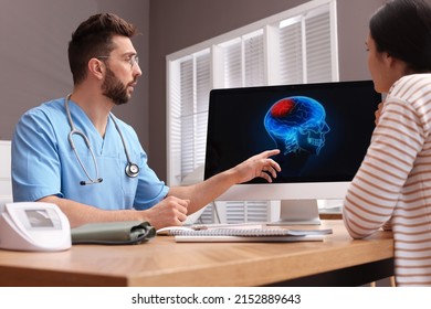 Neurologist showing brain scan to young woman in clinic