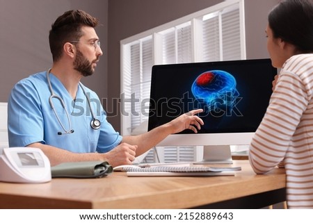 Neurologist showing brain scan to young woman in clinic