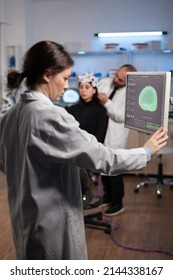 Neurologist Specialist Analyzing Nervous System Tomography On Monitor While Specialist Doctor Adjusting Eeg Scanner Of Woman Patient During Medical Experiment. Neurology Team Monitoring Brain Activity