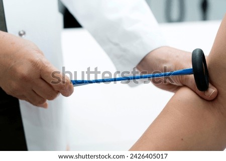 The neurologist testing elbow reflex on a man patient using a hammer. Neurological physical examination. Orthopedist work. Orthopedic surgeon examining checks the physiological reflex test hammer.
