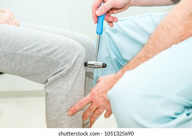 The neurologist testing knee reflex on a female patient using a hammer. Neurological physical examination. Selective focus, close up.