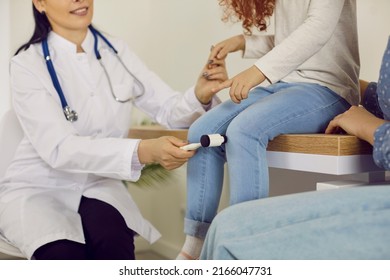 Neurology professional examining little girl. Female doctor uses hammer to test knee jerk patellar reflex. Child and parent having appointment with woman neurologist. Crop shot. Medical background - Powered by Shutterstock
