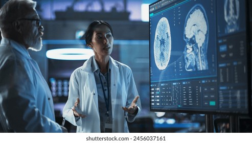 Neuroscience Laboratory Meeting: Female Asian Scientist And Male Caucasian Surgeon Discussing MRI Brain Scan On TV Display. Specialists Working On Medication For Rehabilitation After Brain Damage. - Powered by Shutterstock