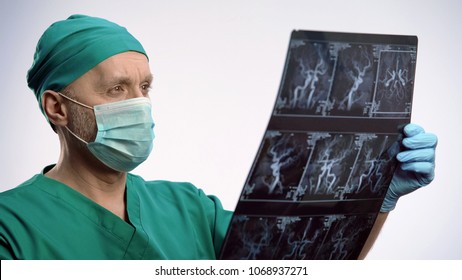 Neurosurgeon In Face Mask Observing MRI Scan, Examining Progress Of Disease