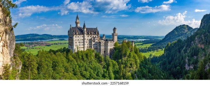 Neuschwanstein castle in a panoramic shot with rocks, trees and horizon in beautiful sunny summer weather - Shutterstock ID 2257168159