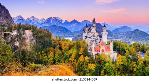 Neuschwanstein Castle (Schloss Neuschwanstein) Bavaria, Germany. Front view of the castle and Queen Mary's bridge at sunrise. The Bavarian Alps in the background.