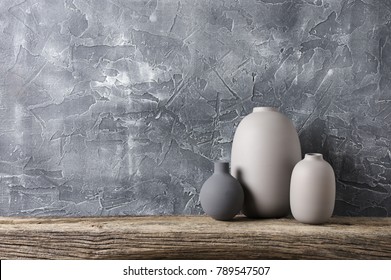 Neutral Colored Vases On Distressed Wooden Shelf Against Rough Plaster Grey Wall. Home Decor.