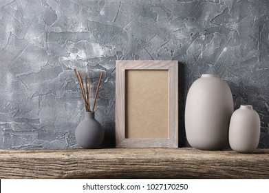 Neutral Colored Vases And Shabby Photoframe On Distressed Wooden Shelf Against Rough Plaster Grey Wall. Home Decor.