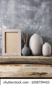 Neutral Colored Vases And Shabby Photoframe On Distressed Wooden Shelf Against Rough Plaster Grey Wall. Home Decor.