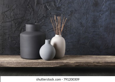 Neutral Colored Vases With Wood Sticks On Distressed Wooden Shelf Against Rough Plaster Black Wall. Home Decor.