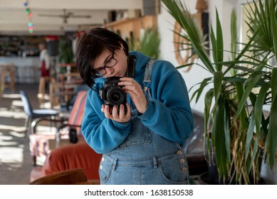 Neutral Gender Teen Photographer Taking Pictures With A Digital Camera In A Sunlit Room