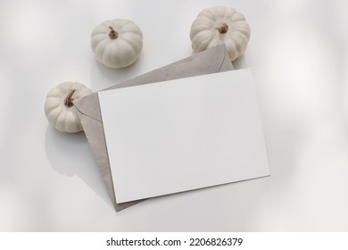 Neutral Halloween Stationery. Mockup Scene With Blank Horizontal Greeting Card, Invitation, Craft Envelope. Little White Pumpkins. Table Background In Sunlight. Autumn, Thanksgiving Concept. Top View.