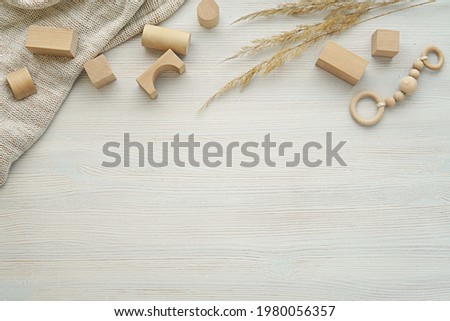 Neutral nursery, baby background, flat lay composition with natural wood building blocks, toys, blanket, dried plants on washed wood table, copy space.
