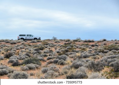 NEVADA, USA - DECEMBER 22, 2016: Blue Toyota Tacoma Pickup Truck Driving On An Empty Desert Road. Blue Sky N The Background, Arid Vegetation In The Foreground. Side View Of Car Driving Through Desert.