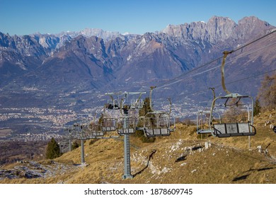 Nevegal, Belluno, Italy - November 26, 2020: Stationary Chairlift Facility Against The Backdrop Of The Belluno Dolomites With Light Haze. Mountains Without Snow. Sunny Day.