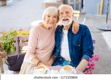 Never boring. Smiling senior couple sitting at cafe and looking at camera - Powered by Shutterstock