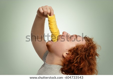 Never enough. Profile of obese Caucasian man with ginger hair leaning head back, about to gobble up big pile of potato chips, helping with hand. Obesity, unhealthy lifestyle and gluttony concept