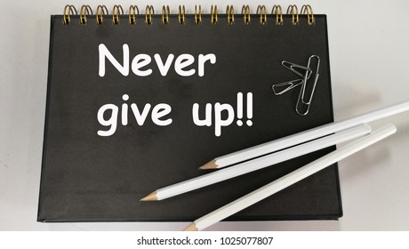 Never give up memo written notebook and pencil   paper clip