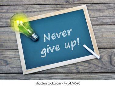 Never give up text school board   glowing light bulb