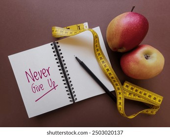 Never Give Up, fitness motivation quote written on notepad. Positive inspirational message on notebook with apples and measuring tape. Motivational workout notes. Sport and healthy lifestyle concept. - Powered by Shutterstock