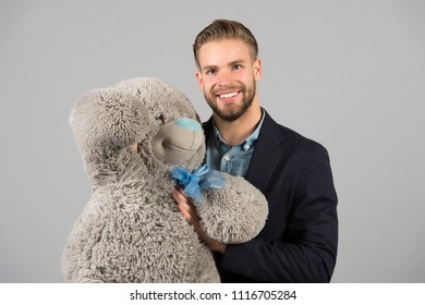 It Is Never Too Late To Have Happy Adulthood. Man Hols Big Teddy Bear, Grey Background. Birthday Gift Concept. Teddy Bear Pleasant Surprise. Guy Happy Hold Bear. Man Cute Gift Surprise. Grown Kid.