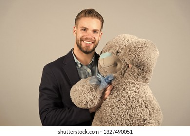 It Is Never Too Late To Have Happy Adulthood. Man Hols Big Teddy Bear, Grey Background. Birthday Gift Concept. Teddy Bear Pleasant Surprise. Guy Happy Hold Bear. Man Cute Gift Surprise. Grown Kid.