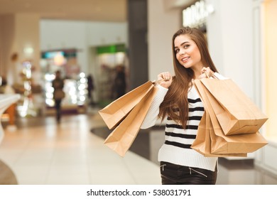 Never Too Much Shopping. Attractive Young Woman Carrying Her Shopping Bags At The Mall Smiling Happily To The Camera Copyspace