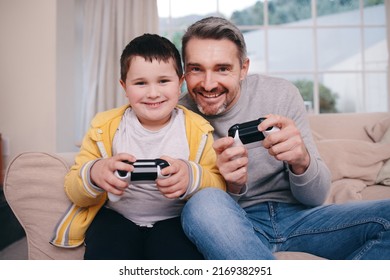 Never A Sore Loser. Shot Of A Father And Son Playing Video Games While Bonding On The Couch At Home.