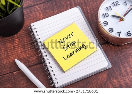  Never Stop Learning text on yellow sticky note on a spiral notebook with clock and pen. Concept for lifelong education, personal growth, and self-improvement.