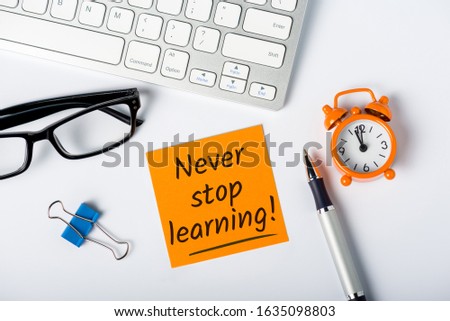 Never stop Learning - written message on white desk workplace. E-learning education concept