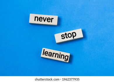 NEVER STOP LEARNING - written on wooden blocks on a blue background. learning concept.
