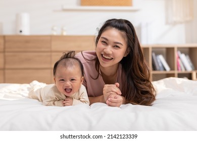New asian mom Newborn baby laying on stomach developing neck control.tummy time for strengthen baby neck and shoulder muscles.Cute infant lying crawling with mother happy and fun.Tummy Time Concept