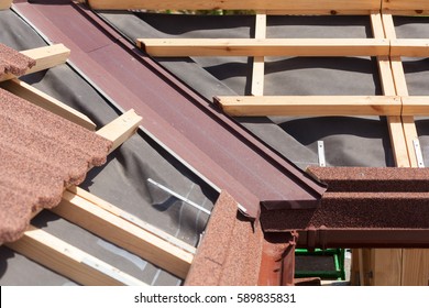 New asphalt shingle roof with brown rain gutter, wooden beams and vapour control layer - Shutterstock ID 589835831
