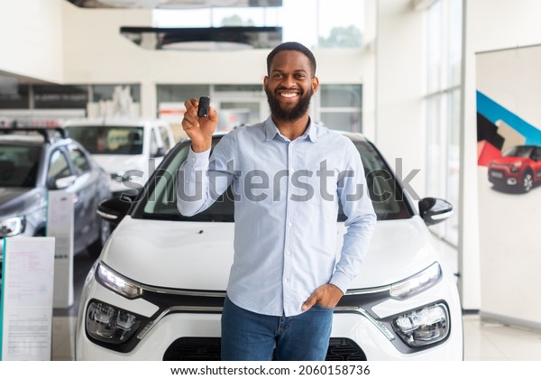New Automobile. Smiling Black Man With Car Keys\
Posing Near Luxury Vehicle, Happy Young African American Male\
Customer Celebrating Purchasing New Auto In Modern Dealership\
Center, Copy Space