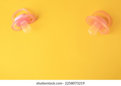 New baby pacifiers on orange background, flat lay. Space for text - Shutterstock ID 2258073219