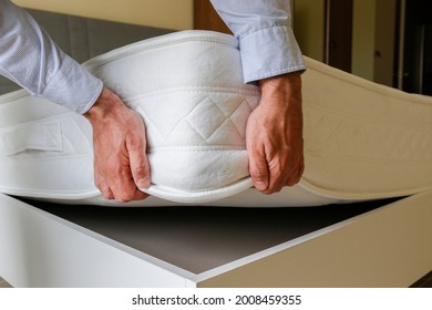 New Bed Delivery And Assembly Service Concept. Cropped Shot Of Male Worker's Hands In Process Of Laying The Orthopedic Foam Mattress On Carcass In Customer's Bedroom. Close Up, Copy Space, Background.