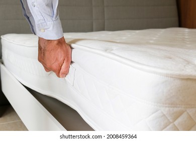 New Bed Delivery And Assembly Service Concept. Cropped Shot Of Male Worker's Hands In Process Of Laying The Orthopedic Foam Mattress On Carcass In Customer's Bedroom. Close Up, Copy Space, Background.