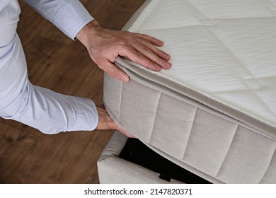 New Bed Delivery And Assembly Service Concept. Cropped Shot Of Male Worker's Hands In Process Of Laying The Orthopedic Foam Mattress On Carcass In Customer's Bedroom. Close Up, Copy Space, Background.