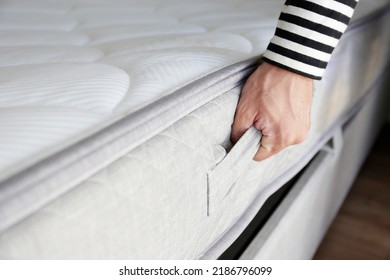 New Bed Delivery And Assembly Service Concept. Cropped Shot Of Male Worker's Hands In Process Of Laying The Orthopedic Foam Mattress On Carcass In Customer's Bedroom. Close Up, Copy Space, Background.