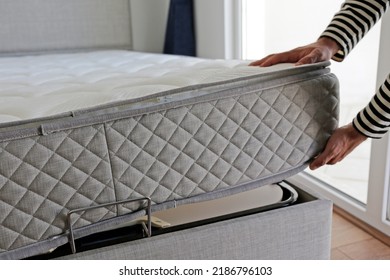 New Bed Delivery And Assembly Service Concept. Cropped Shot Of Male Worker's Hands In Process Of Laying The Orthopedic Foam Mattress On Carcass In Customer's Bedroom. Close Up, Copy Space, Background.