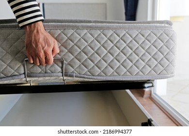 New Bed Delivery And Assembly Service Concept. Cropped Shot Of Male Worker In Process Of Laying Orthopedic Foam Mattress On Carcass, Showing The Storage Compartment. Close Up, Copy Space, Background.