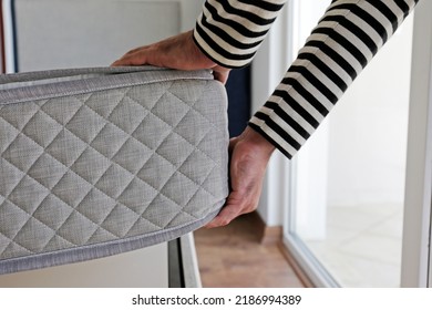 New Bed Delivery And Assembly Service Concept. Cropped Shot Of Male Worker's Hands In Process Of Laying The Orthopedic Foam Mattress On Carcass In Customer's Bedroom. Close Up, Copy Space, Background.