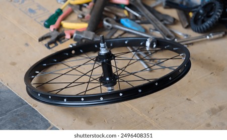 A new bicycle wheel rests on a workshop table surrounded by essential bike repair tools. - Powered by Shutterstock