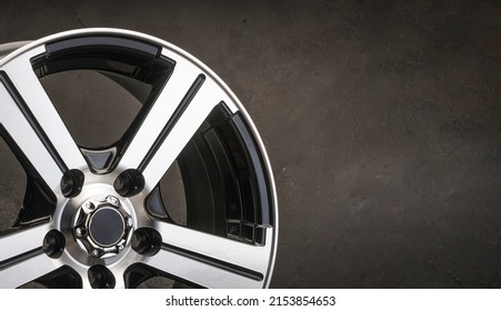 new black alloy wheels on a dark textured black background. wheel for car spare parts auto repair tire shop, copy space panorama empty