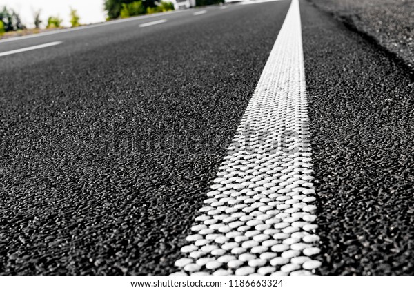 New black asphalt road and\
dividing lines from white dots. Textural background of\
asphalt.