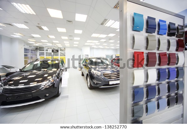 New black cars stand\
in car shop near stand with samples of paint for body. Focus on\
stand with samples.
