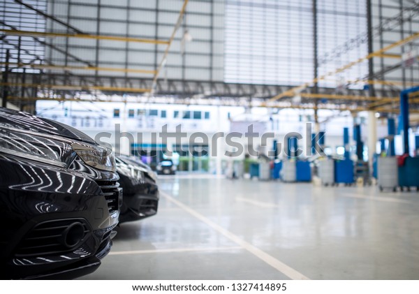 New black cars in stock,\
parking waiting for sale In the service repair center. The electric\
lift for cars in the service put on the epoxy floor in new car\
factory service