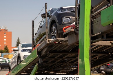 New Black Crossover - SUV On Car Carrier Trailer, Car-carrying Trailer, Car Hauler, Auto Transport Trailer, Semi-trailer. Front-side View. Visible Headlights.